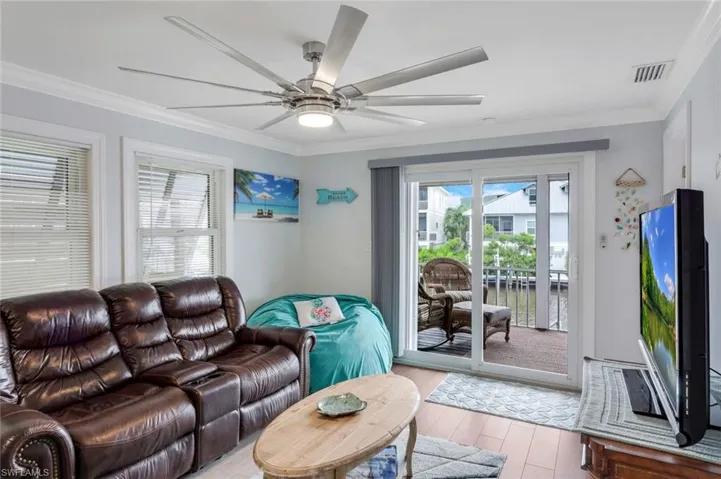 Living room featuring crown molding, wood finished floors, healthy amount of natural light, and a ceiling fan