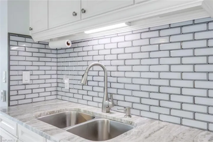 Kitchen featuring white cabinetry, light stone countertops, and backsplash