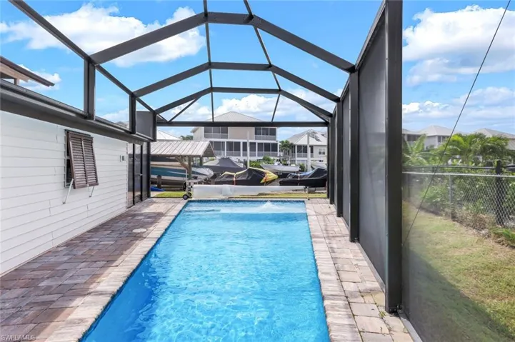 Outdoor pool featuring glass enclosure, a sunroom, and a patio