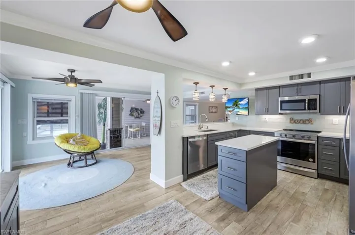 Kitchen featuring stainless steel appliances, tasteful backsplash, gray cabinetry, a center island, and ornamental molding