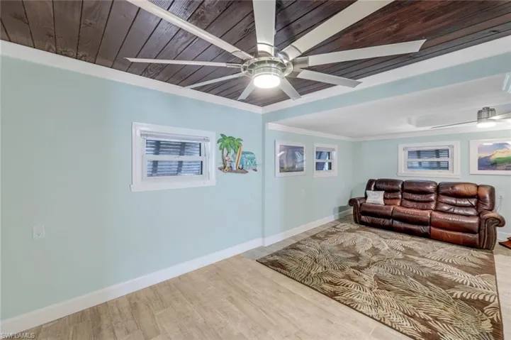 Living area with wood finished floors, ceiling fan, ornamental molding, and wood ceiling