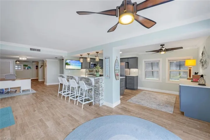 Kitchen featuring a breakfast bar area, light wood finished floors, crown molding, hanging light fixtures, and stainless steel microwave