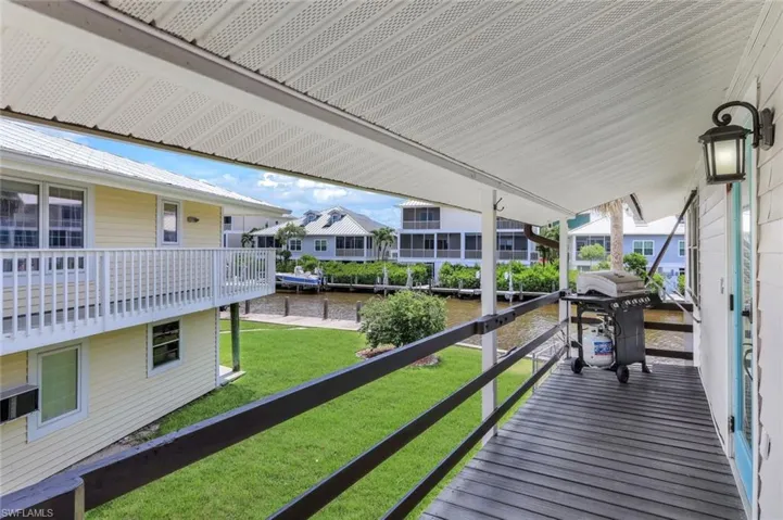 Wooden deck featuring grilling area, a water view, a lawn, and a residential view
