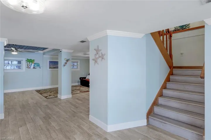 Stairway with wood finished floors and crown molding