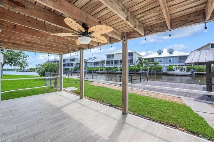 View of patio featuring a water view, a dock, ceiling fan, and a residential view