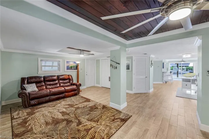 Living area featuring plenty of natural light, light wood-style flooring, a ceiling fan, wood ceiling, and ornamental molding