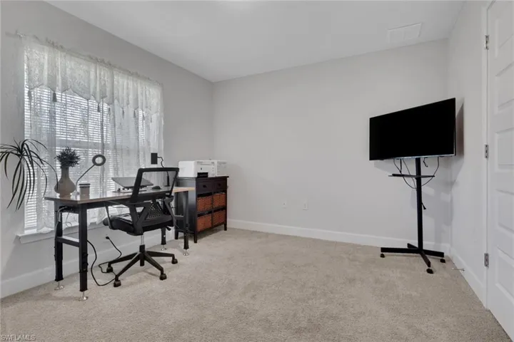 Neutral-toned room featuring a window with blinds, light gray wall paint, and light gray carpeted flooring