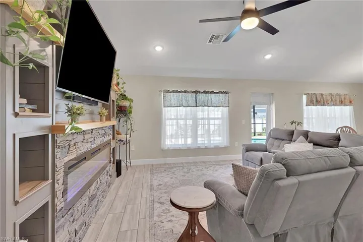 Living area featuring a stone-faced electric fireplace with a built-in media center, recessed lighting, and a ceiling fan
