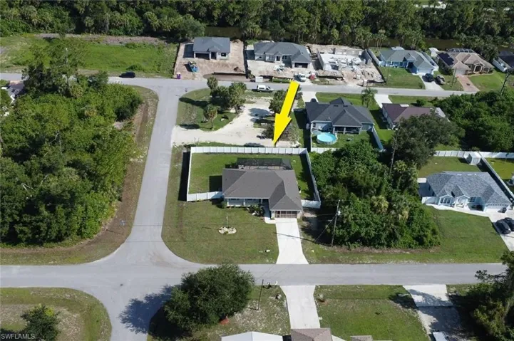 Expansive corner lot featuring a well-maintained lawn, privacy fencing, a paved driveway, and mature landscaping