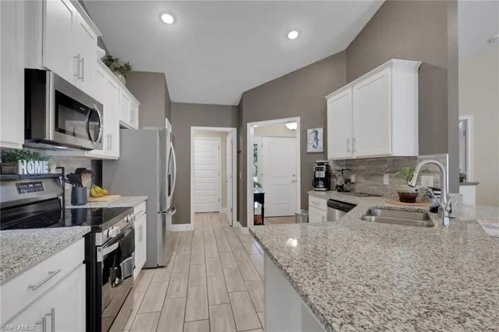 Modern kitchen featuring white cabinetry, stainless steel appliances, and granite countertops