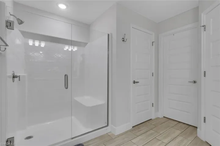 Glass-enclosed shower with a built-in bench and a tiled accent wall