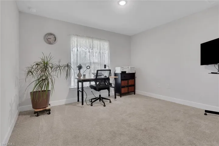 Spacious room featuring neutral carpeting, light-toned walls, and white baseboards