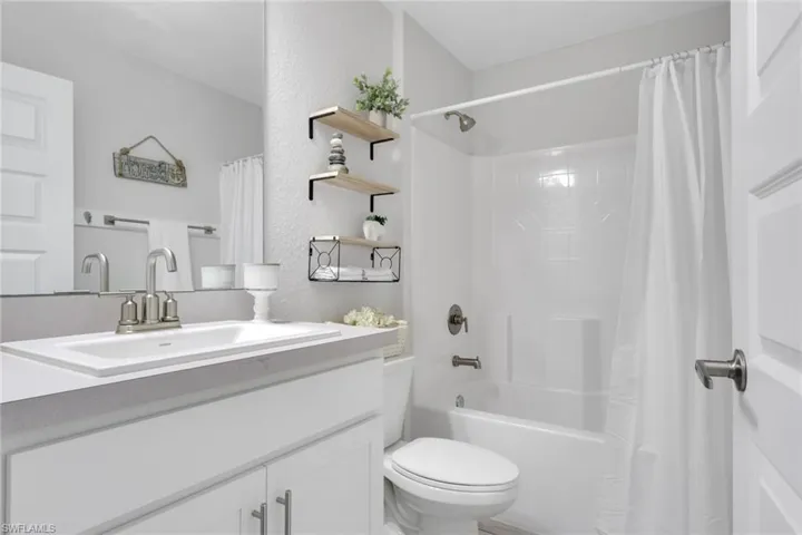 Bathroom featuring a white vanity with integrated sink, brushed nickel faucet, and a spacious mirror