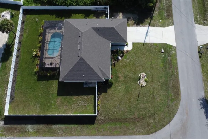 Property featuring a screened-in swimming pool, a private fenced yard, a corner lot, and a paved driveway