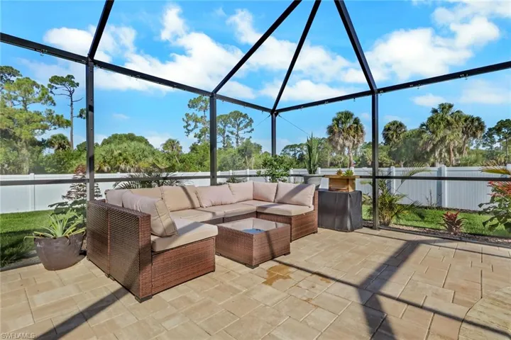 Expansive screened patio featuring paver flooring, a white privacy fence, and mature landscaping