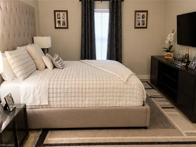 Spacious room with light-toned walls, wood-finish flooring, and a large window with privacy blinds