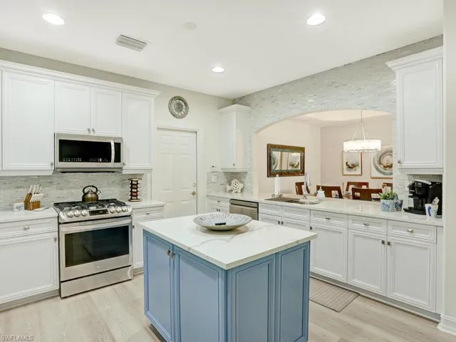 Kitchen with blue cabinetry, appliances with stainless steel finishes, white cabinetry, and recessed lighting