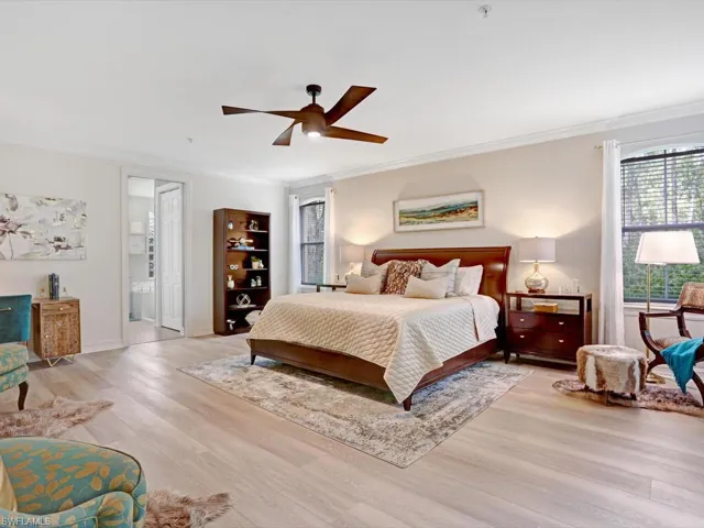 Bedroom featuring wood finished floors, crown molding, and a ceiling fan
