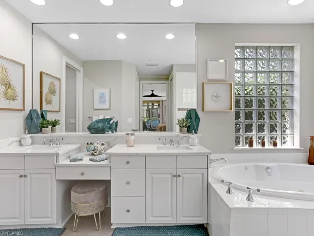 Full bath with double vanity, a garden tub, recessed lighting, and a ceiling fan