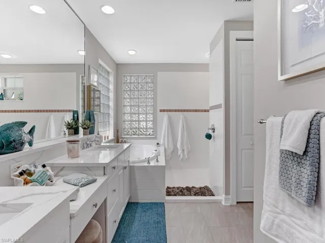 Bathroom featuring vanity, a bath, light tile patterned flooring, and a shower