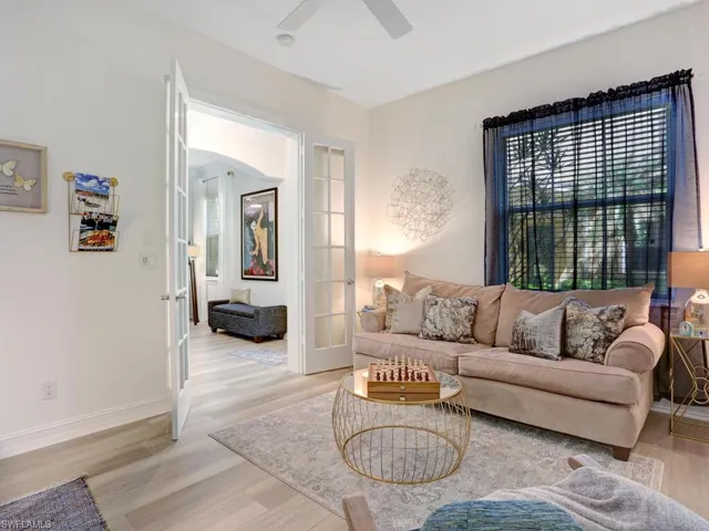 Living room with wood finished floors, french doors, ceiling fan, and arched walkways