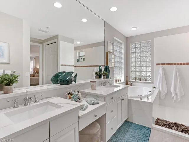 Full bath featuring double vanity, ensuite bathroom, a garden tub, and light tile patterned floors