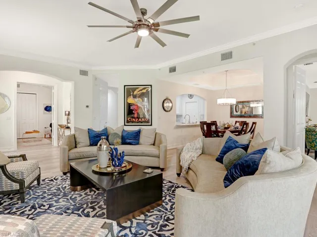 Living room with arched walkways, crown molding, wood finished floors, and a ceiling fan
