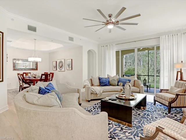 Living room featuring crown molding, wood finished floors, a ceiling fan, and a tray ceiling