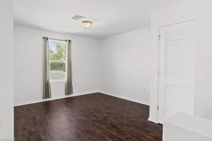 Spare room featuring dark wood-style flooring