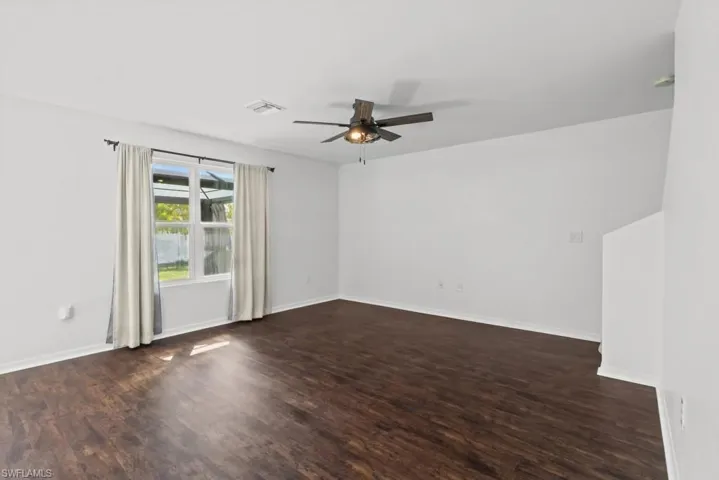Unfurnished room with dark wood finished floors and ceiling fan