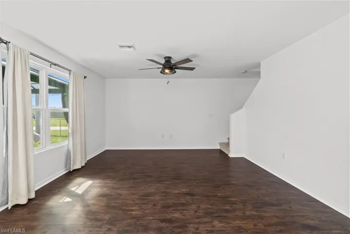 Unfurnished living room with a ceiling fan and dark wood-style floors