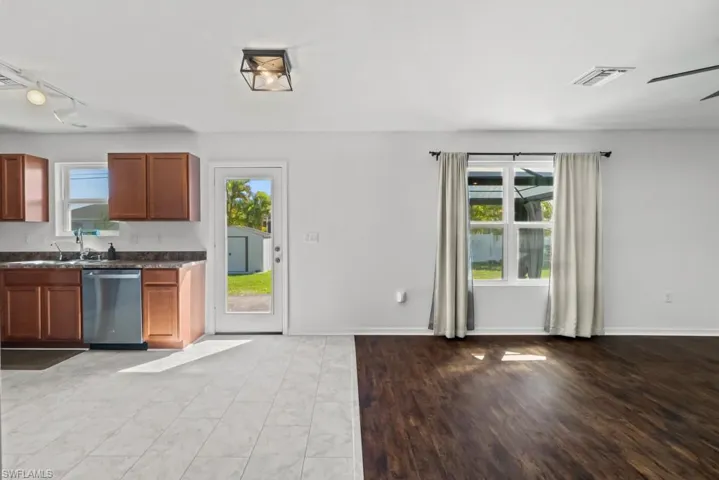 Kitchen with wood finish cabinets, dishwasher, track lighting, light wood-style flooring, and a ceiling fan
