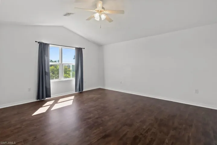 Empty room with dark wood-type flooring and ceiling fan