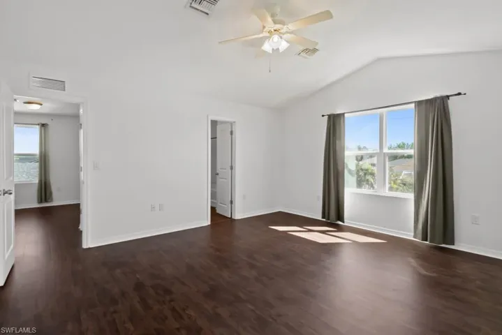Spare room with ceiling fan, dark wood-style floors, and lofted ceiling