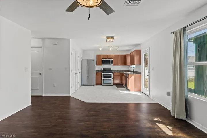 Kitchen with ceiling fan, stainless steel appliances, wood finish cabinets, dark wood finished floors, and open floor plan