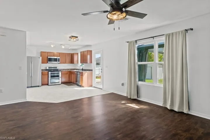 Kitchen with open floor plan, light wood-style floors, stainless steel appliances, wood finish cabinetry, and ceiling fan