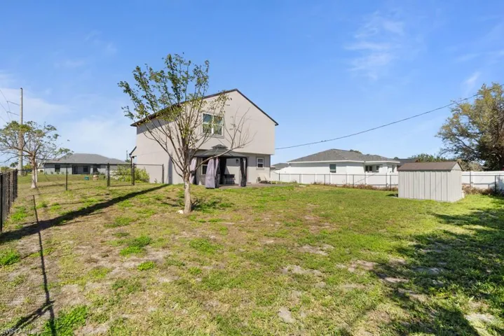 Rear view of house with a fenced backyard, a shed, stucco siding, and a patio area
