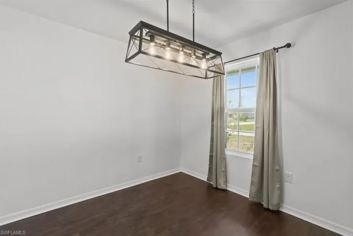 Unfurnished dining area featuring dark wood-type flooring and baseboards
