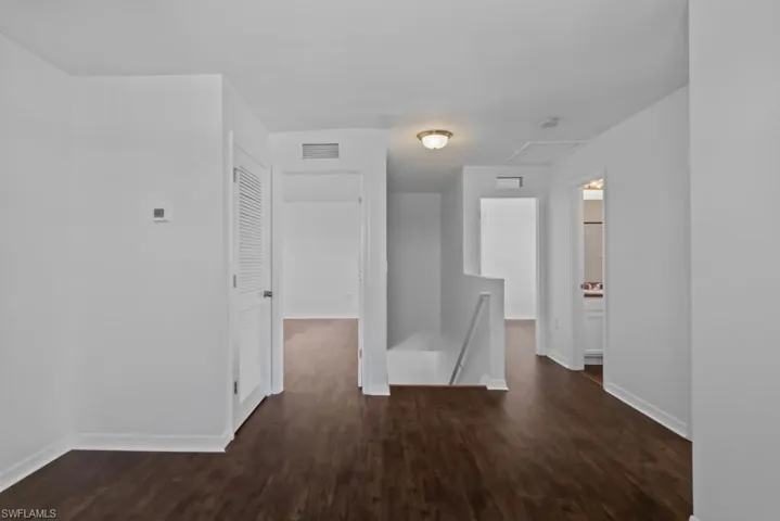 Hall with an upstairs landing and dark wood-style flooring