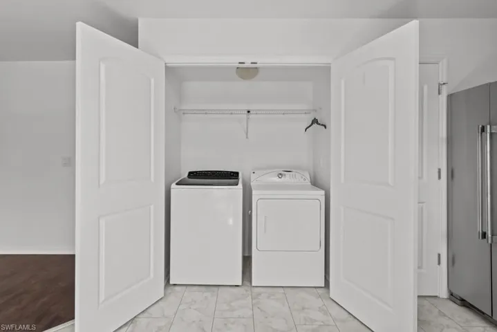 Laundry area featuring washing machine and dryer and light marble finish flooring