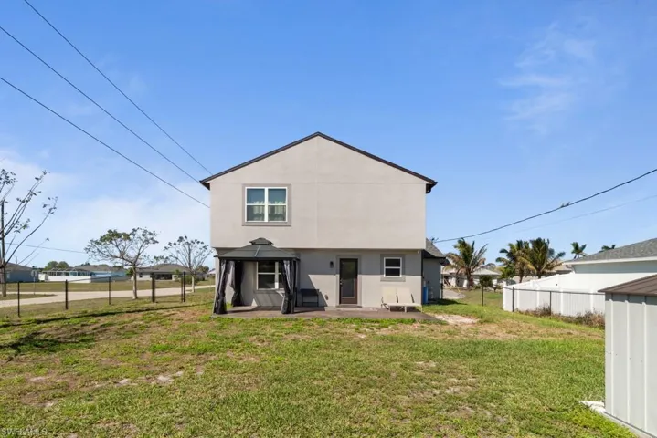 Rear view of property with stucco siding, a patio area, and a fenced backyard