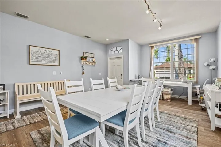 Dining space featuring arched walkways, rail lighting, baseboards, and wood finished floors