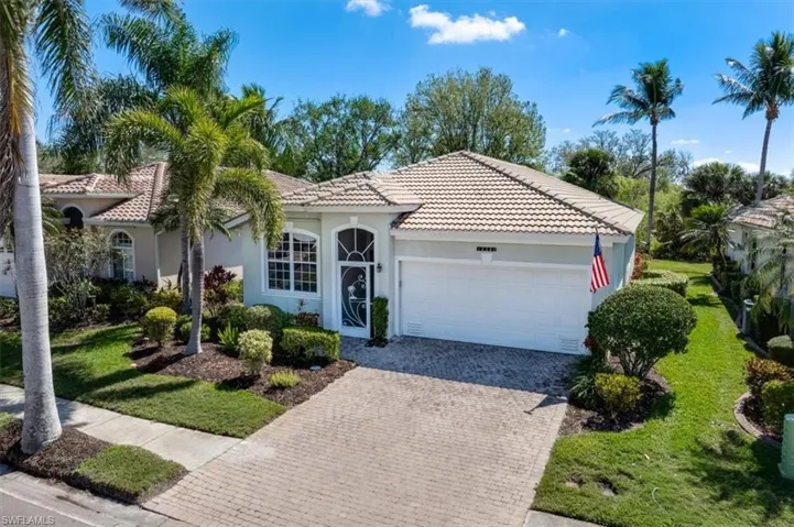 View of front of property with a front lawn, a tile roof, stucco siding, decorative driveway, and an attached garage