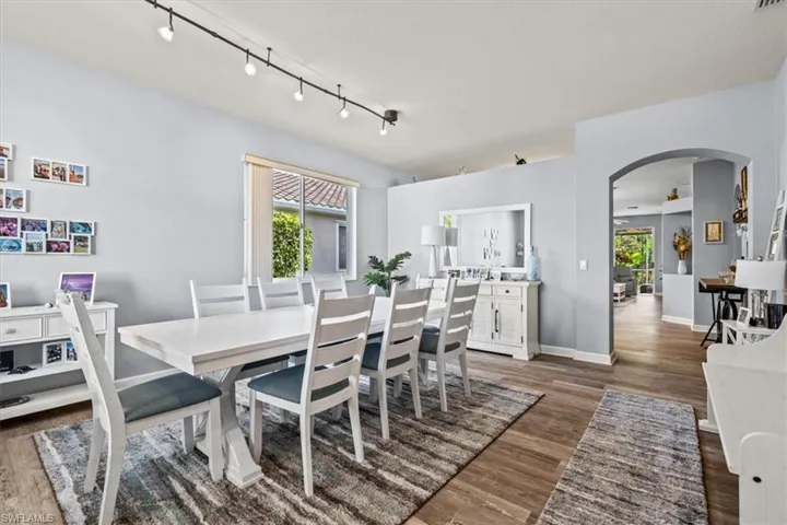 Dining space featuring visible vents, baseboards, arched walkways, and light wood finished floors