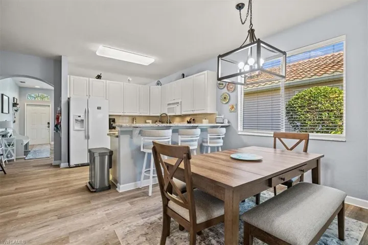Dining area with an inviting chandelier, arched walkways, a wealth of natural light, and light wood-type flooring