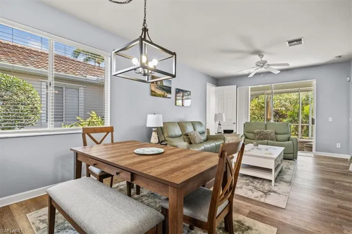 Dining space with visible vents, baseboards, wood finished floors, and ceiling fan with notable chandelier