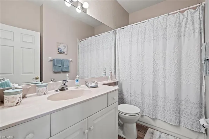 Full bath with toilet, wood finished floors, and vanity