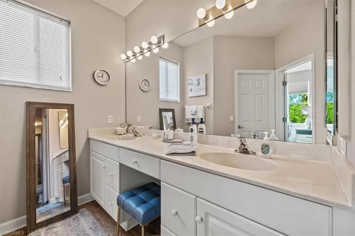 Full bath with double vanity, baseboards, and a sink