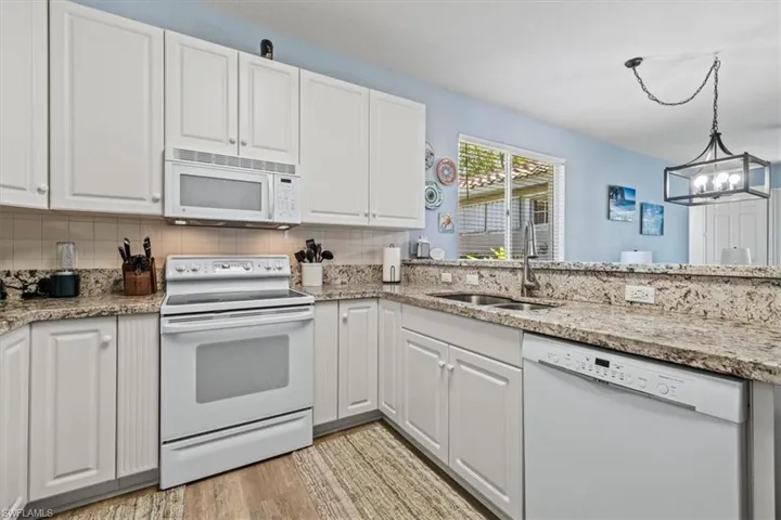 Kitchen featuring visible vents, a sink, wood finished floors, arched walkways, and dishwasher