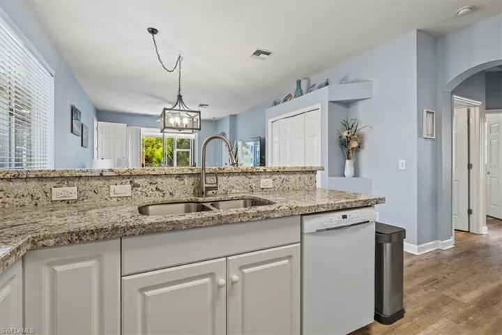 Kitchen with decorative backsplash, white appliances, arched walkways, and white cabinetry